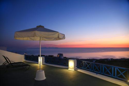 a patio with an umbrella and a table and chair at Pergeri Apartments in Imerovigli