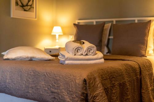a bed with a pile of towels on it at Hotel Ô Château in Hayange