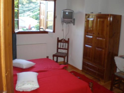 Schlafzimmer mit einem roten Bett und einem TV in der Unterkunft Archontiko Samara in Áno Lekhónia