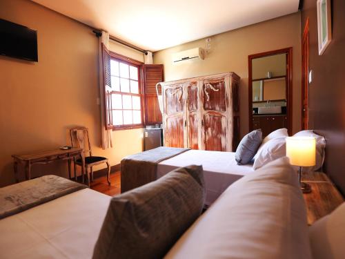 a hotel room with two beds and a television at Hotel Gambrinus in Poços de Caldas