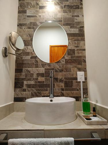 HOTEL ANTHURIUM في Jalcomulco: حمام مع حوض ومرآة على منضدة