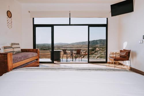 a living room with a bed and a large window at Siempre Valle Hotel Boutique in Valle de Guadalupe