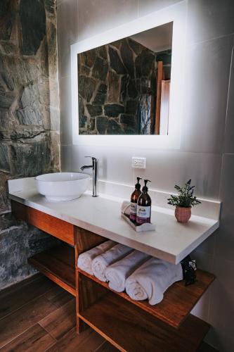 a bathroom with a sink and a mirror and towels at Siempre Valle Hotel Boutique in Valle de Guadalupe