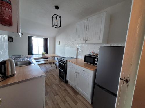 a kitchen with white cabinets and a black refrigerator at Sea view Penthouse flat 6 with fast WiFi and Free PARKING in Scarborough