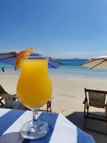 a glass of orange juice sitting on a table on the beach at Pousada Seven in Arraial do Cabo