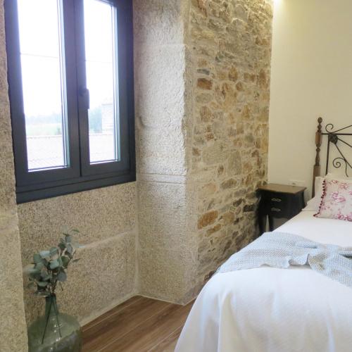 sypialnia z łóżkiem i ceglaną ścianą w obiekcie Casa Leonor de Aurora w mieście Zas