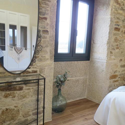 1 dormitorio con espejo y un jarrón con flores en Casa Leonor de Aurora en Zas