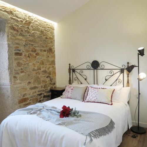 a bedroom with a white bed with a stone wall at Casa Leonor de Aurora in Zas