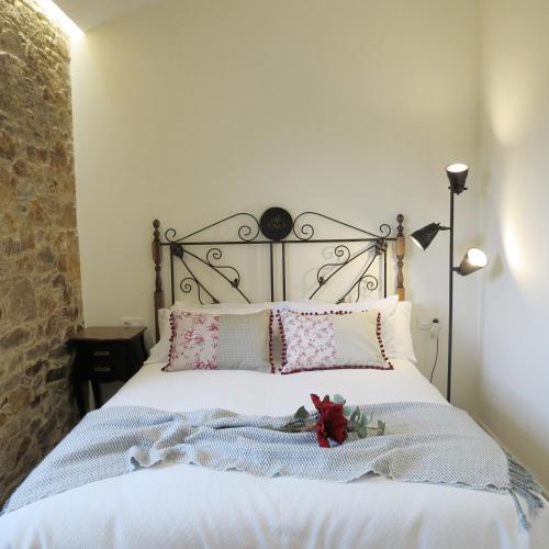 a bedroom with a bed with white sheets and pink pillows at Casa Leonor de Aurora in Zas