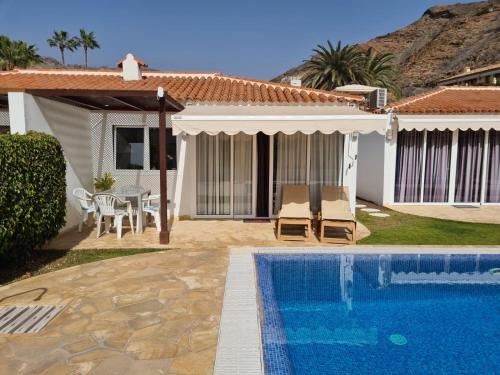 a villa with a swimming pool and a house at Apartamento relax Tauro in Mogán