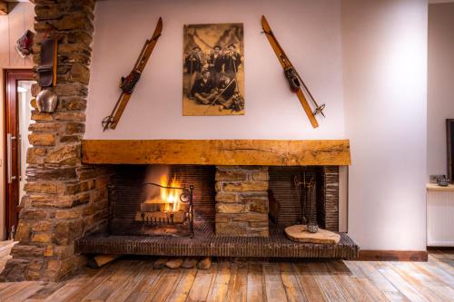 a living room with a stone fireplace with guns on the wall at Hôtel La Rencluse in Luchon
