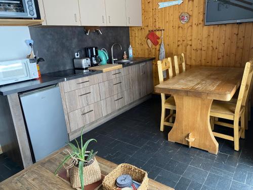 une cuisine avec une table en bois et un micro-ondes dans l'établissement LES AMBRUNES, à Châtel