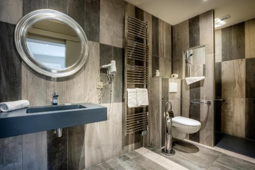 a bathroom with a sink and a toilet and a mirror at Hôtel La Rencluse in Luchon