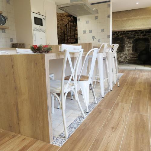 a row of white chairs sitting at a kitchen counter at Casa Leonor de Aurora in Zas