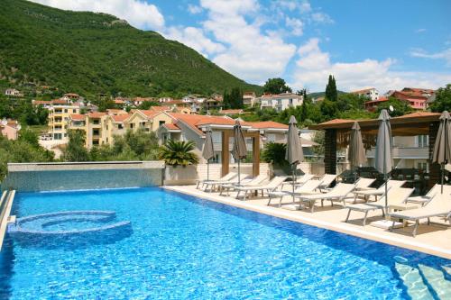 una piscina con tumbonas y una montaña en Apart Hotel Sun Village en Herceg-Novi