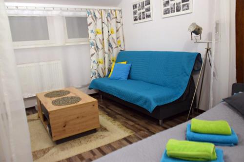 a living room with a blue couch and a table at Apartament Górnicza w Kowarach in Kowary