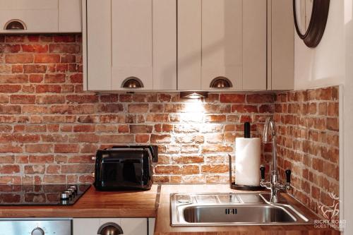 a kitchen with a sink and a brick wall at Ricky Road Guest House - Premium in Watford