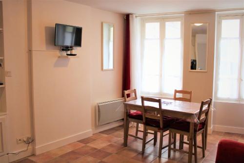 ein Esszimmer mit einem Tisch und Stühlen sowie einem TV an der Wand in der Unterkunft Gîte de Ponpon, à proximité du Zoo et des Châteaux de la Loire in Selles-sur-Cher