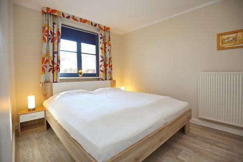 um quarto com uma cama grande e uma janela em Feriendorf Papillon Wohnung 10-3 em Boltenhagen