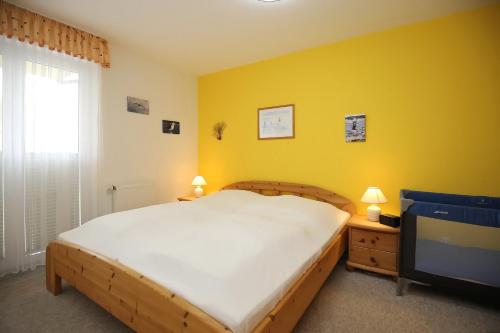 een slaapkamer met een groot bed en een gele muur bij Nordstern Wohnung 12 in Boltenhagen