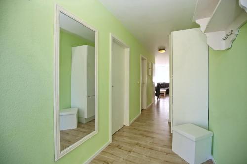 un couloir avec des murs verts et un miroir dans l'établissement Feriendorf Papillon Wohnung 05-7, à Boltenhagen