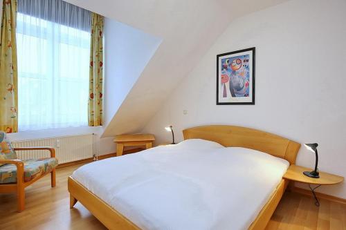 a bedroom with a bed and a chair and a window at Sünnslag Wohnung 148 in Boltenhagen