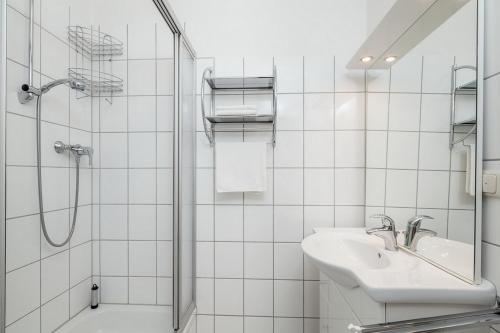 ein weißes Bad mit einem Waschbecken und einer Dusche in der Unterkunft Sünnslag Wohnung 148 in Boltenhagen