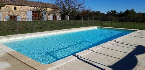 une piscine avec de l'eau bleue devant une maison dans l'établissement Les Roses, à Barjou