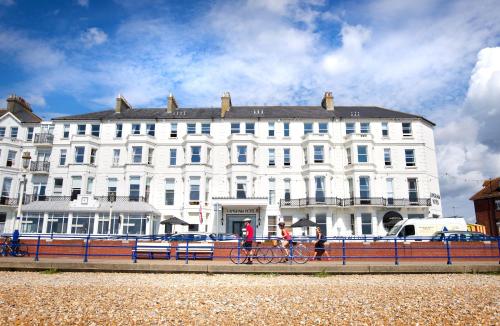two people riding bikes in front of a white building at Langham Hotel Eastbourne in Eastbourne