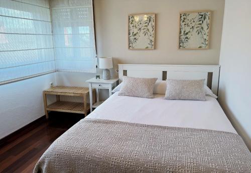 een slaapkamer met een wit bed en een raam bij Santiago Apartment in Santiago de Compostela