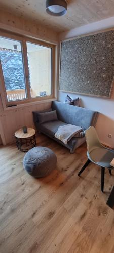 a living room with a blue couch and some windows at Apartment Almwiesen Mellau in Mellau