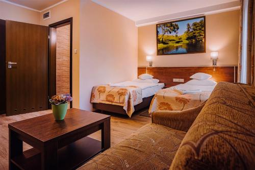 アウグストゥフにあるVilla Skomandaのベッド2台とソファが備わるホテルルームです。