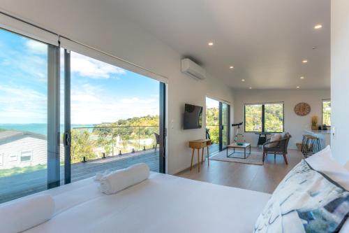 a bedroom with a white bed and a large window at Luna Cottage. Stunning ocean views on Waiheke in Oneroa