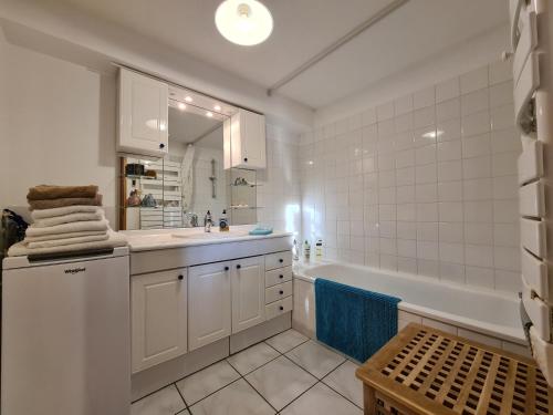 La salle de bains blanche est pourvue d'une baignoire, d'un lavabo et d'une baignoire. dans l'établissement Large private garden, quiet 2-bedroom apartment, air conditioning, wifi, parking, à Cassis