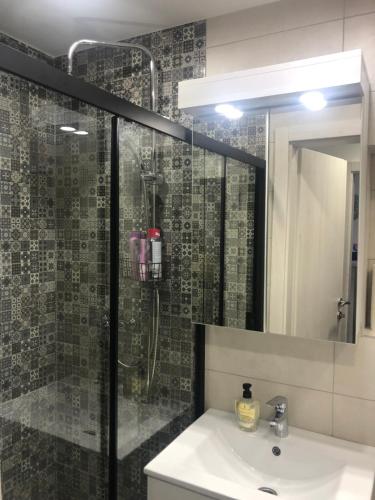 a bathroom with a shower and a sink and a mirror at Mini apartman Smile in Travnik