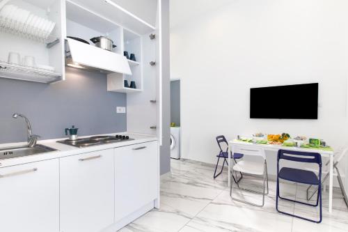 a kitchen with white cabinets and a table with chairs at Piazza Tasso Max 1 in Sorrento