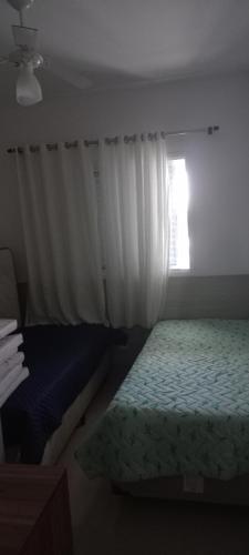 um quarto com uma cama e uma janela em Apartamento Bertioga Centro em Bertioga