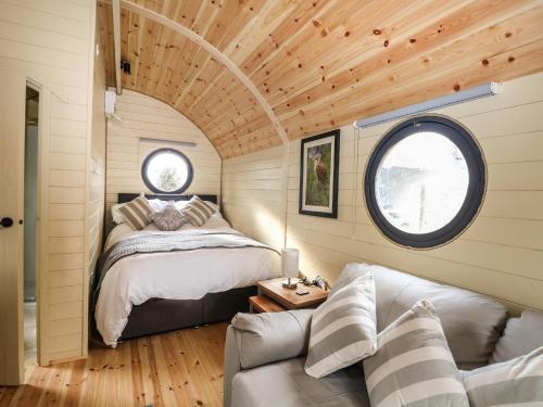 a bedroom in a tiny house with a bed and a couch at Willow Pod in Arundel