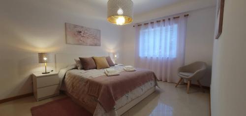 a bedroom with a bed and a chair and a window at Apartamento Dionisio in Albufeira