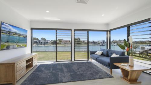 a living room with a blue couch and large windows at FLOATING ON THE CANALS - 80 COMMODORE CRES in Port Macquarie