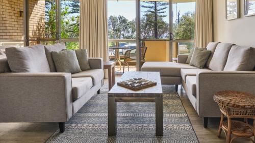 a living room with couches and a table at Perfectly Positioned Beachfront Apartment - Unit 6 in Port Macquarie