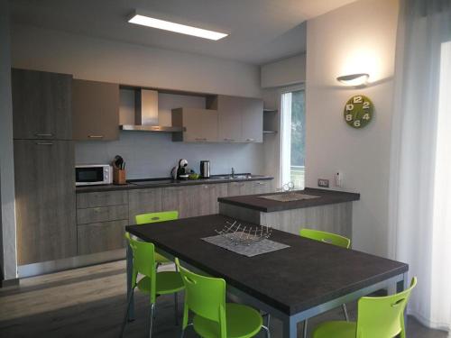 a kitchen with a dining table and green chairs at La Svolta Holidays in Malcesine