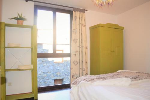 1 dormitorio con 1 cama, armario verde y ventana en Apartament acollidor amb una gran llar de foc by RURAL D'ÀNEU, en Esterri d'Àneu