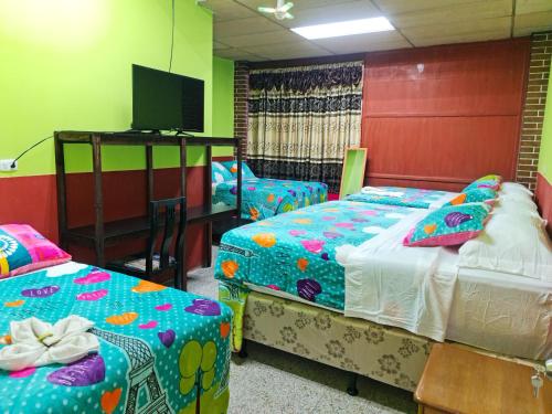 Habitación con 3 camas y TV. en Hotel Kasa Kamelot Las Rosas, en Quetzaltenango