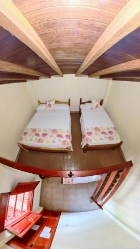 two beds in a small room with wooden ceilings at La Casa de las Flores Hostal in Jardin