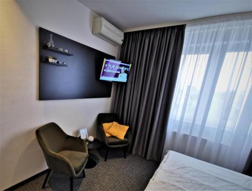 Habitación de hotel con cama, TV y silla en FiORE self check-in en Osijek