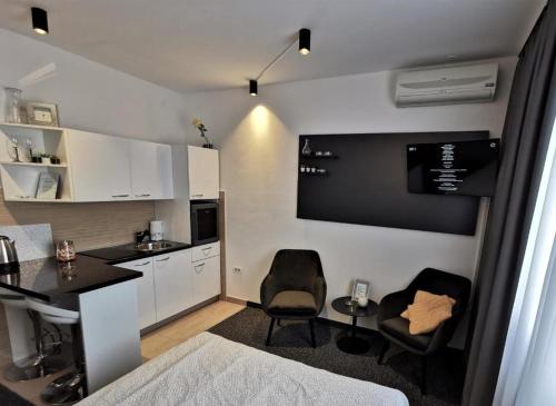 uma cozinha com duas cadeiras e uma mesa num quarto em FiORE self check-in em Osijek