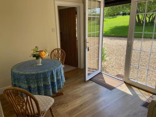 a room with a table with a vase of flowers on it at Oke Apple Cottage in Shillingstone