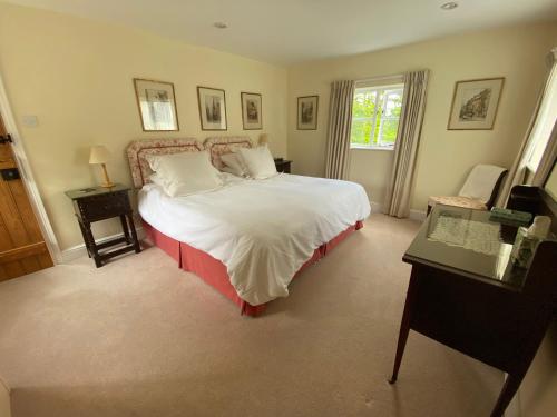 a bedroom with a bed and a desk and a window at Oke Apple Cottage in Shillingstone