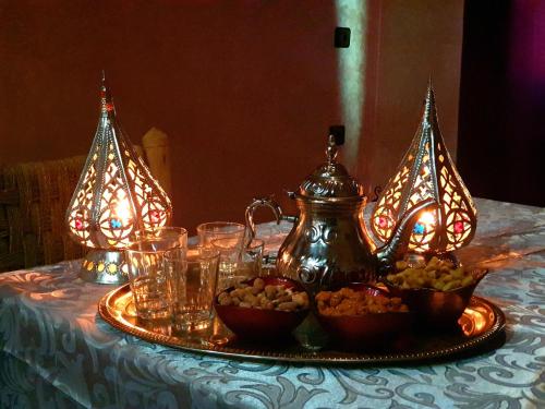 a table with a plate of food and a tea kettle at Hôtel Bia Besta in Boumalne